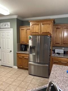 kitchen with light countertops, ornamental molding, light tile patterned flooring, and stainless steel fridge with ice dispenser