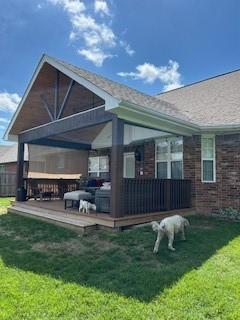back of property featuring a wooden deck and a yard