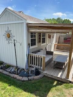 back of property featuring a deck and an outbuilding