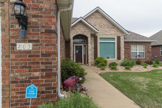 203 W Hayden Blvd, Rogers, AR 72756 - property entrance with brick siding, a shingled roof, stone siding, and a yard
