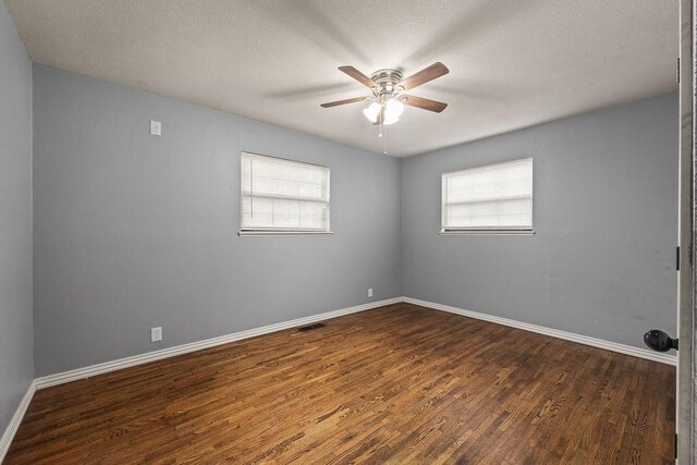 empty room with baseboards, a textured ceiling, dark wood finished floors, and ceiling fan