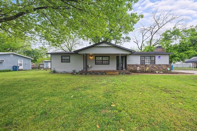 view of front of property featuring fence, a chimney, a porch, and a front lawn