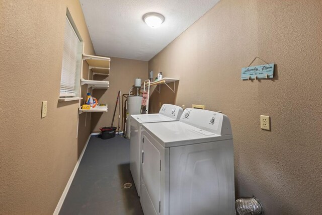 laundry area featuring a textured wall, laundry area, separate washer and dryer, water heater, and baseboards