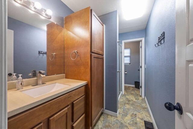 full bath featuring visible vents, stone finish flooring, baseboards, and vanity
