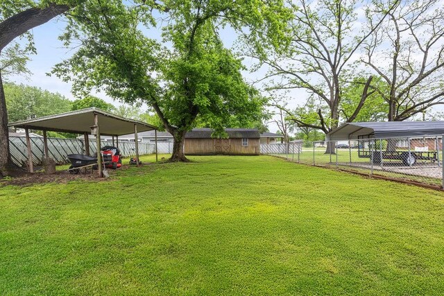 view of yard with fence, a detached carport, and driveway