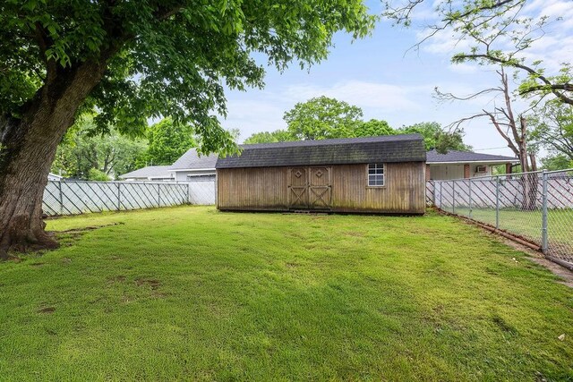 view of yard with a fenced backyard, an outdoor structure, and a storage shed