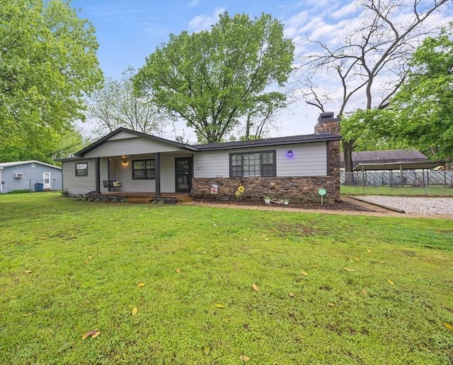 ranch-style home featuring fence, stone siding, a front yard, a chimney, and a porch