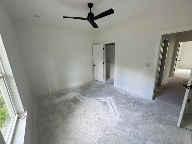 unfurnished bedroom with ceiling fan and a spacious closet