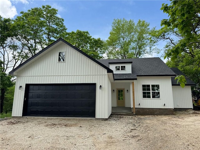 modern inspired farmhouse featuring roof with shingles, dirt driveway, and an attached garage