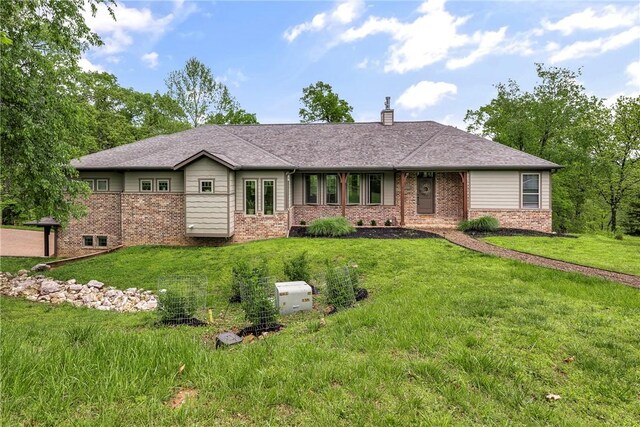 ranch-style house featuring brick siding, a front yard, and a chimney