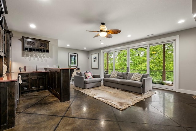 living room featuring recessed lighting, wet bar, ceiling fan, and finished concrete flooring