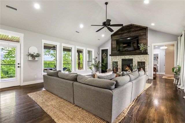living room featuring ceiling fan, visible vents, a stone fireplace, and a wealth of natural light