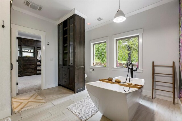 bathroom featuring baseboards, a wealth of natural light, a soaking tub, and visible vents