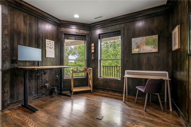 interior space with crown molding, wood walls, wood finished floors, and visible vents