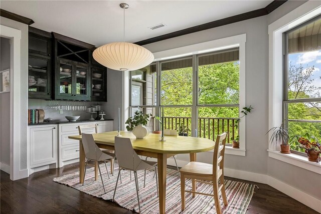 dining space with visible vents, baseboards, dark wood-type flooring, and bar
