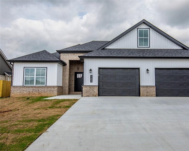 view of front of home with brick siding, a front lawn, concrete driveway, an attached garage, and a shingled roof