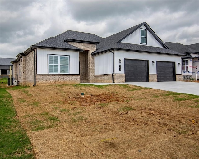 view of front of house featuring a garage, brick siding, a shingled roof, central air condition unit, and driveway