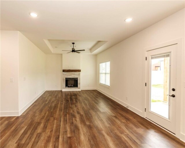 unfurnished living room featuring a fireplace, ceiling fan, recessed lighting, a raised ceiling, and dark wood finished floors
