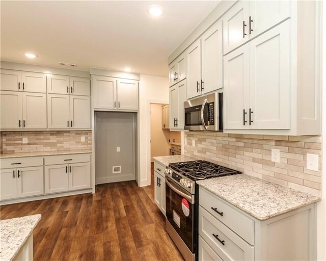kitchen with light stone countertops, tasteful backsplash, stainless steel appliances, recessed lighting, and dark wood-type flooring