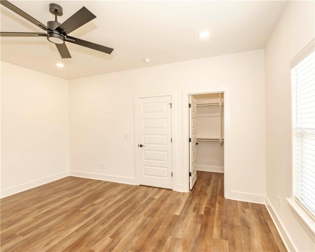 unfurnished bedroom with baseboards, multiple windows, and light wood-style floors