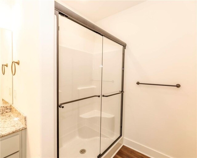 full bathroom with vanity, baseboards, a shower stall, and wood finished floors