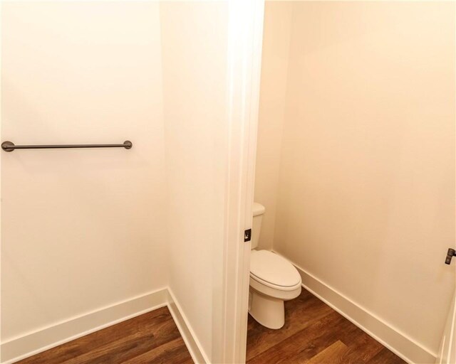 bathroom with baseboards, toilet, and wood finished floors