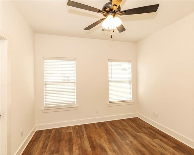 unfurnished room featuring visible vents, dark wood-style flooring, ceiling fan, and baseboards
