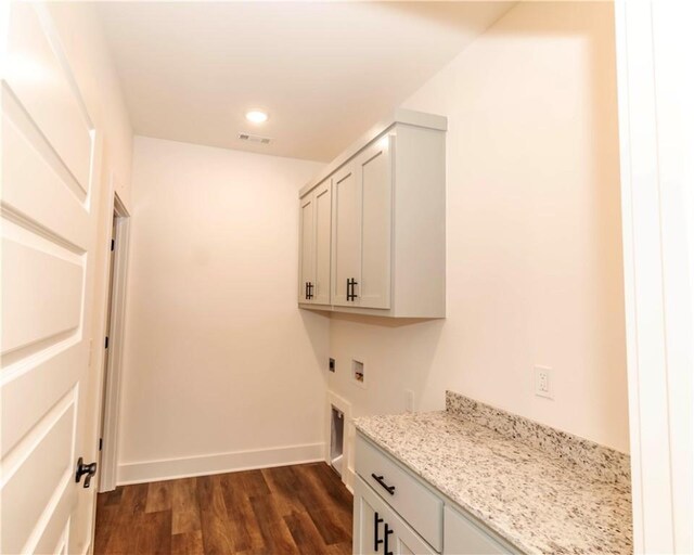 clothes washing area with washer hookup, electric dryer hookup, dark wood finished floors, cabinet space, and baseboards