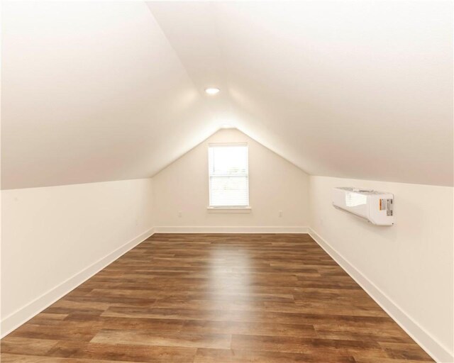 additional living space with baseboards, a wall mounted air conditioner, lofted ceiling, and wood finished floors