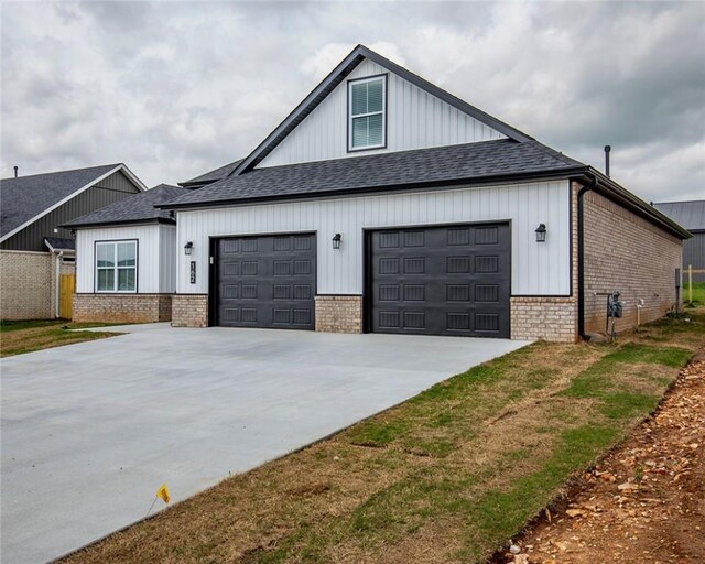 view of side of property with a garage, a shingled roof, driveway, and brick siding