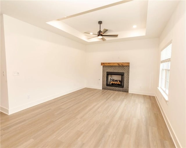 212 Nebo St, Prairie Grove, AR 72753 - unfurnished living room with a ceiling fan, a raised ceiling, light wood-style floors, and a tiled fireplace