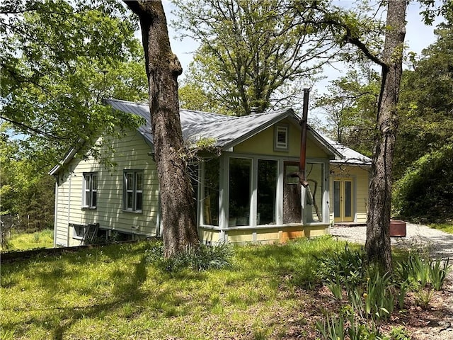 rear view of property featuring a sunroom and metal roof