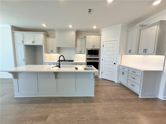 kitchen featuring visible vents, ornamental molding, oven, built in microwave, and a sink