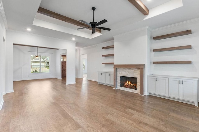 909 Budrio Ave, Tontitown, AR 72762 - unfurnished living room featuring a stone fireplace, a ceiling fan, light wood-style floors, ornamental molding, and a tray ceiling