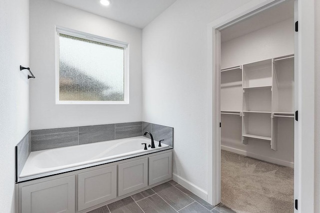 909 Budrio Ave, Tontitown, AR 72762 - bathroom featuring a spacious closet, a bath, and baseboards