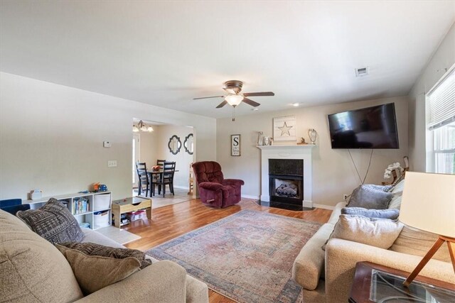 5213 S 62nd St, Rogers, AR 72758 - living area featuring wood finished floors, a ceiling fan, a fireplace with flush hearth, and baseboards
