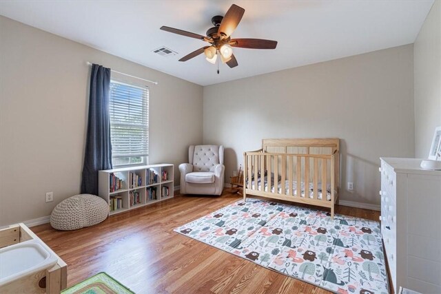 5213 S 62nd St, Rogers, AR 72758 - bedroom with wood finished floors, a crib, and a ceiling fan