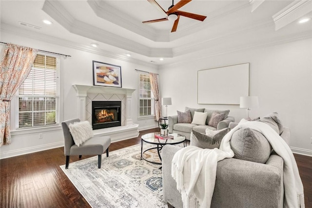 living room featuring ceiling fan, visible vents, crown molding, wood finished floors, and a glass covered fireplace