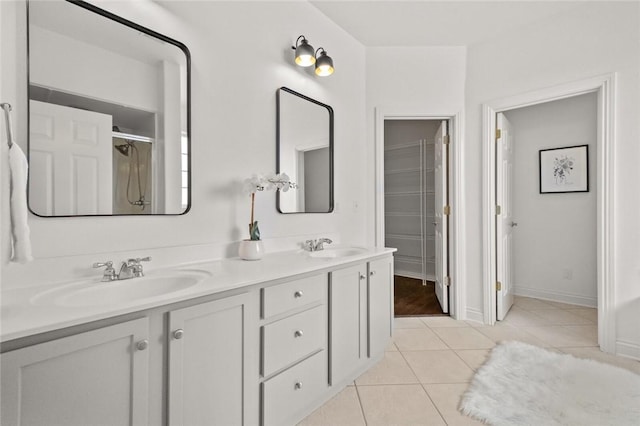 bathroom with baseboards, double vanity, tile patterned floors, and a sink