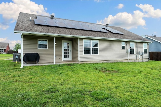 rear view of property with a lawn, a patio area, heating fuel, and solar panels