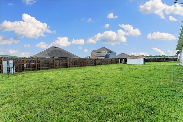 view of yard with an outbuilding, a fenced backyard, and a storage unit