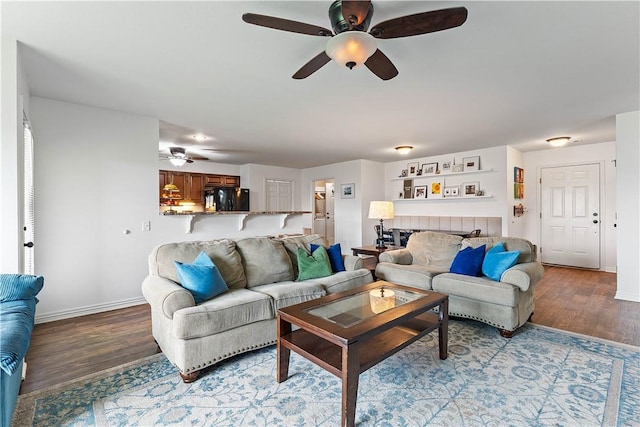 living room featuring baseboards, a ceiling fan, and wood finished floors