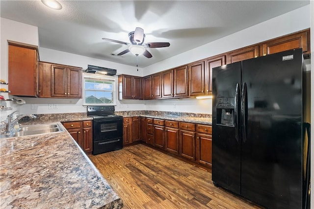 kitchen with a sink, dark wood-style flooring, ceiling fan, and black appliances