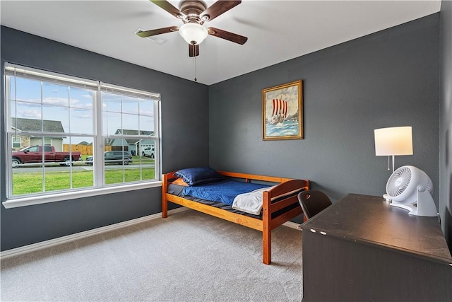 carpeted bedroom featuring baseboards, multiple windows, and ceiling fan