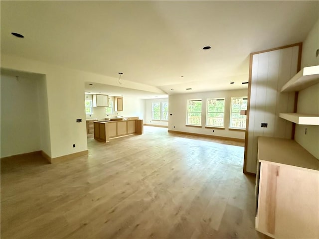 unfurnished living room featuring baseboards and light wood finished floors