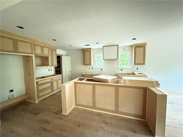 kitchen featuring light brown cabinetry, a center island, and wood finished floors