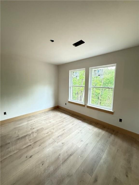 spare room with baseboards and light wood-style flooring