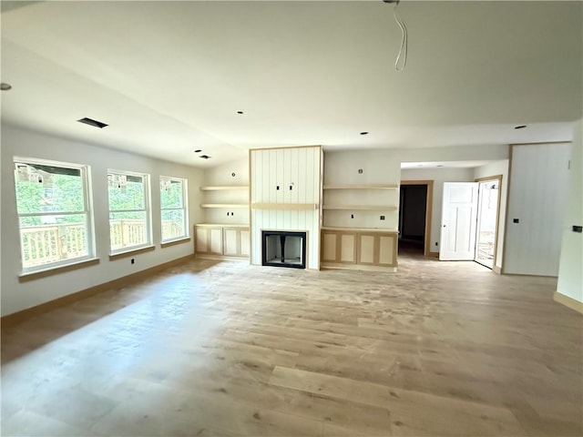 unfurnished living room with light wood-style floors, baseboards, and a large fireplace