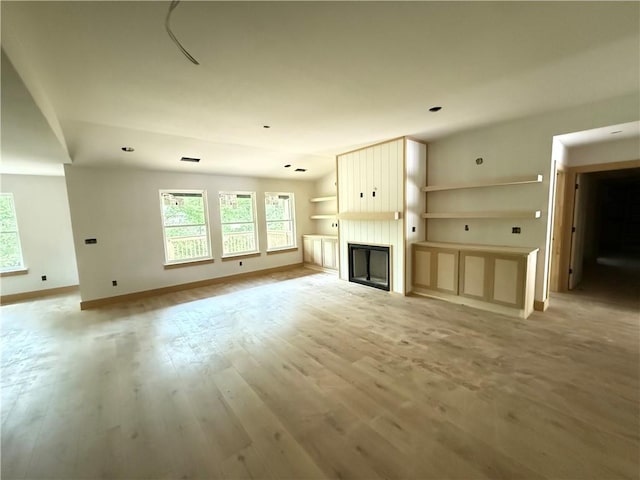 unfurnished living room featuring a large fireplace, plenty of natural light, baseboards, and light wood-type flooring