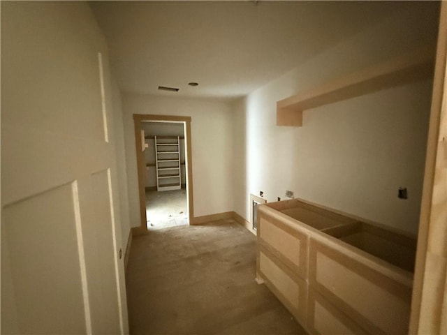 hall featuring baseboards, light colored carpet, and visible vents